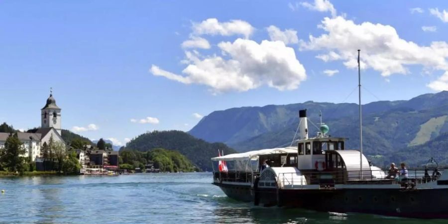 Ein Boot fährt über den Wolfgangsee. In der kleinen Gemeinde sind in den vergangenen Tagen mehr als 60 Corona-Tests positiv ausgefallen. Foto: Kerstin Joensson/AP/dpa