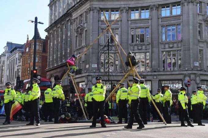 Polizisten stehen vor den Holzstangen auf der Kreuzung. Extinction Rebellion - London