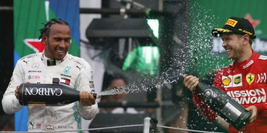 Champus für den Sieger: Lewis Hamilton feiert, Sebastian Vettel zwangsläufig mit. Foto: Rebecca Blackwell/AP/dpa