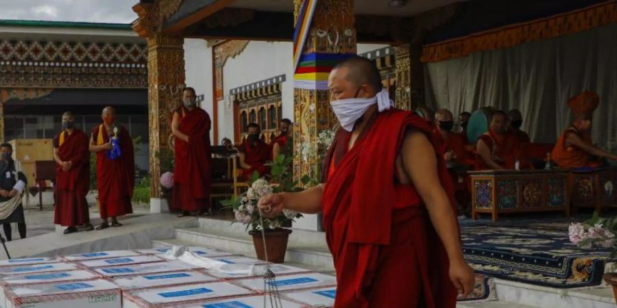 Mönche des Klosters von Paro führen ein Ritual durch, nachdem 500.000 Dosen des von den USA gespendeten Corona-Impfstoffs von Moderna am internationalen Flughafen von Paro ankamen. Foto: Uncredited/UNICEF/AP/dpa