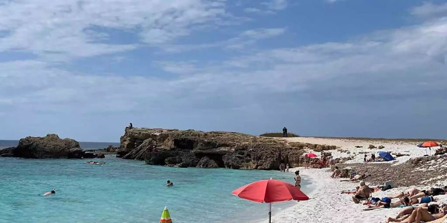 ARCHIV - Menschen liegen am Strand von Is Arutas an der Westküste Sardiniens. Urlauber und Bewohner in Italien müssen sich in den kommenden Tagen auf extreme Hitze einstellen. Für Dienstag und Mittwoch gab das Gesundheitsministerium am Montag für einige Teile Italiens die höchste Hitze-Stufe drei heraus. Foto: Annette Reuther/dpa - ACHTUNG: Verwendung nur im vollen Format