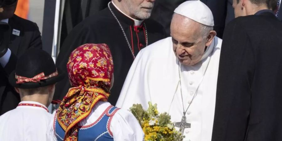 Papst Franziskus wird von zwei Kindern in traditioneller Kleidung am Flughafen im slowakischen Bratislava empfangen. Foto: Pavel Neubauer/TASR/dpa