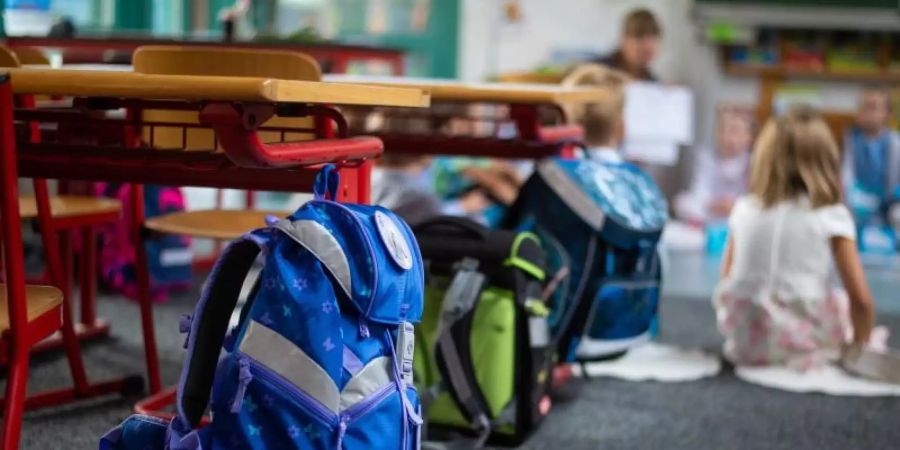 Ranzen hängen und stehen beim Begrüssungsunterricht der neuen Erstklässler im Klassenzimmer. (Archivbild). Foto: Philipp Schulze/dpa