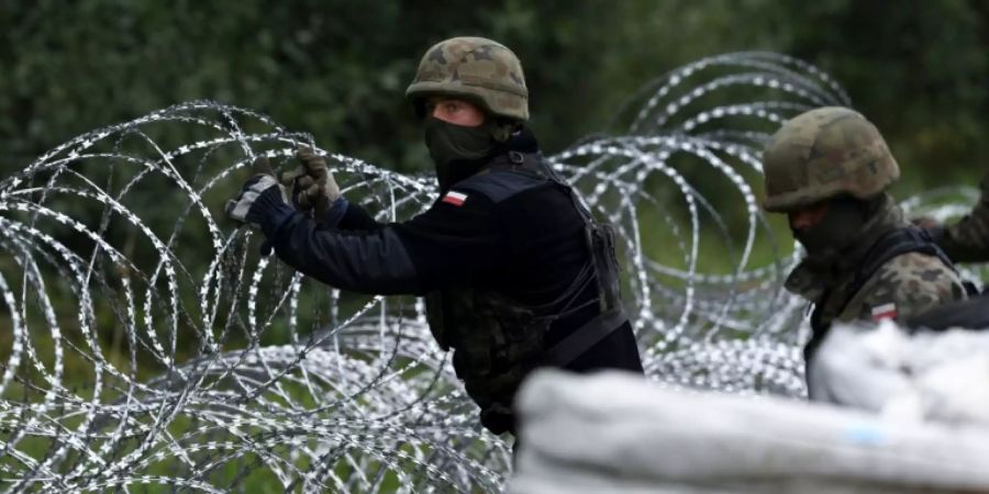 Polnische Soldaten bauen einen Grenzzaun aus Stacheldraht an der Grenze zu Belarus