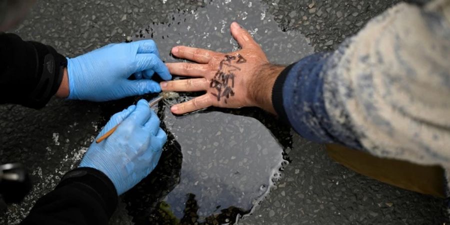 Polizisten entfernen Kleber von der Hand eines Demonstranten