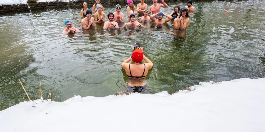 Mitglieder der Gruppe «Munich Hot Springs» baden bei eisigen Temparaturen und Schneefall in einem Nebenarm des Eisbachs im Englischen Garten in München.