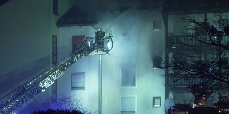 Feuerwehrleute sind bei einem Brand in einem Mehrfamilienwohnhaus in Bayern im Einsatz.