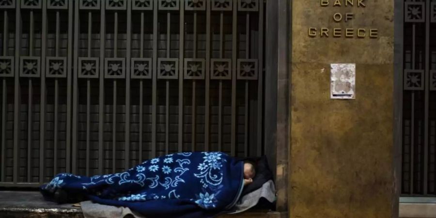 Ein Obdachloser hat sich vor der Bank von Griechenland in Athen zum Schlafen gelegt. Foto: Angelos Tzortzinis