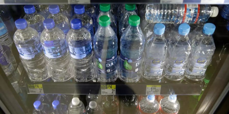 Einweg-Plastikflaschen mit Wasser stehen in einem Geschäft im Kühlschrank.