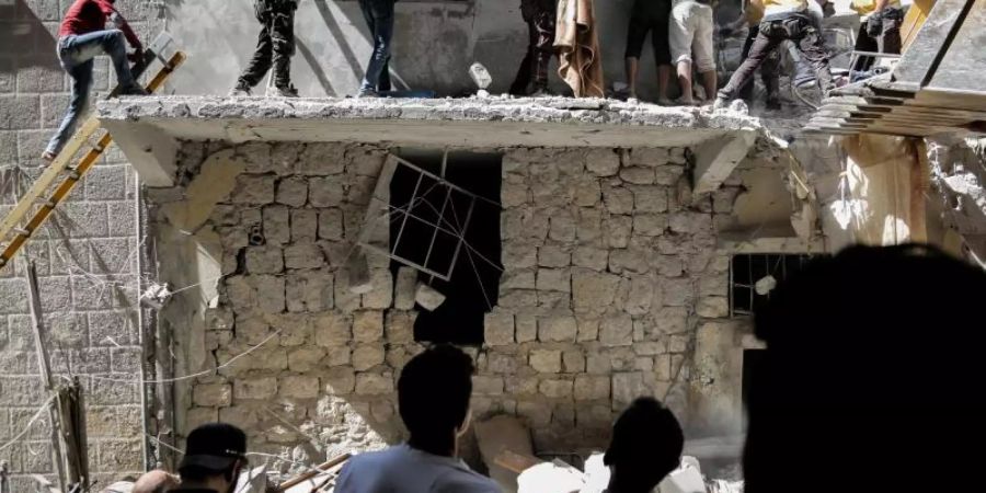 Menschen stehen vor einem Gebäude, das bei einem Luftangriff am 27. Mai durch die syrischen Regierungskräfte beschädigt wurde. Foto: Anas Alkharboutli