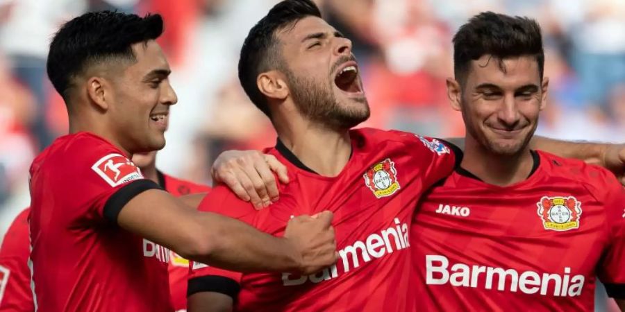 Torschütze Kevin Volland (M) jubelt mit Nadiem Amiri (l) und Lucas Alario (r) über das 1:0 gegen Union Berlin. Foto: Federico Gambarini