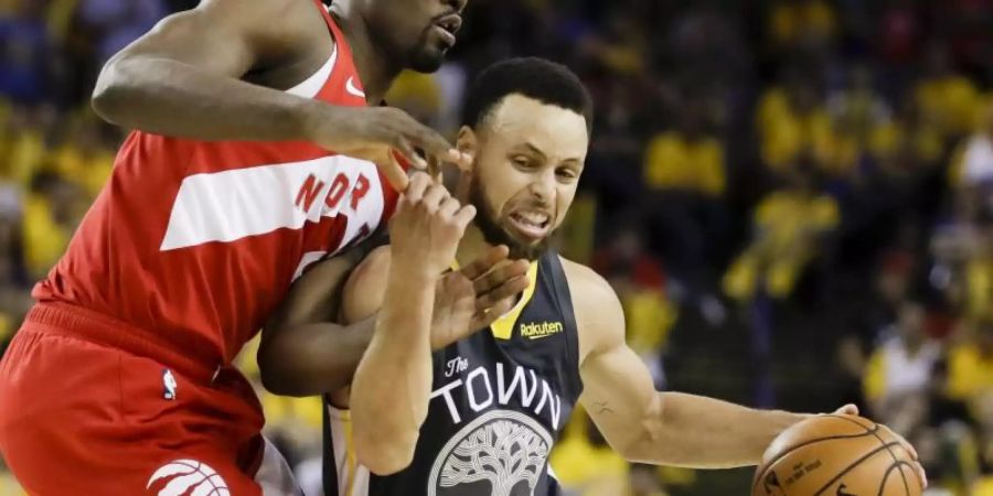 Stephen Curry (r) von den Golden State Warriors behauptet sich gegen Serge Ibaka von den Toronto Raptors. Foto: Ben Margot/AP