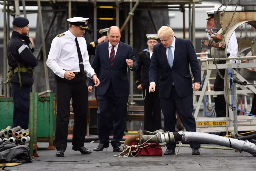 Boris Johnson (r), Premierminister von Grossbritannien, und Ben Wallace (M), Verteidigungsminister von Grossbritannien, werden von dem Kommandeur Justin Codd bei ihrem Besuch des U-Boots HMS