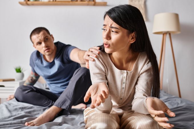Die Eifersucht auf vergangene Beziehungen hängt häufig mit eigener Unsicherheit oder Ängsten zusammen. Frau und Mann bei einer Diskussion auf dem Bett