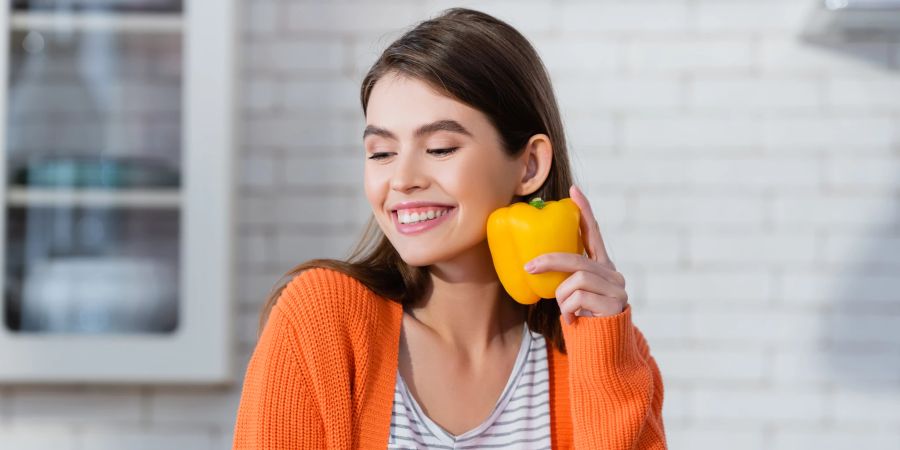 Lächelnde Frau mit Paprika in der Hand