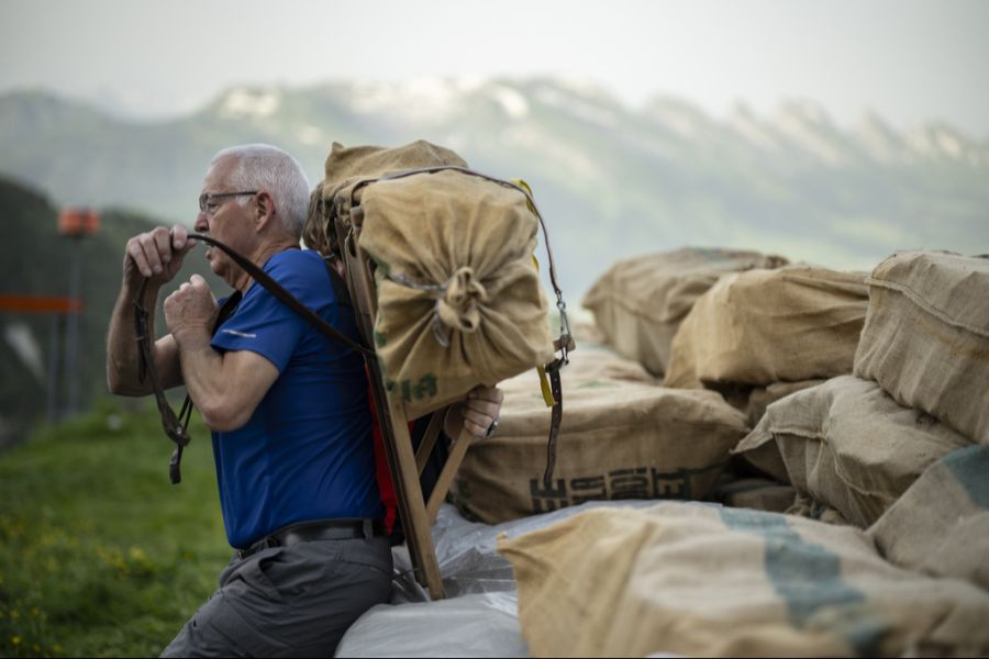Der freiwillige Träger Daniel Scherrer lädt Holz auf, bei der traditionellen «Hötteträgete» zur Zwinglipasshütte SAC auf 1999 m ü. M., im Juni 2024. Freiwillige tragen jeweils acht Tonnen Material von der Chreialp zur Hütte.