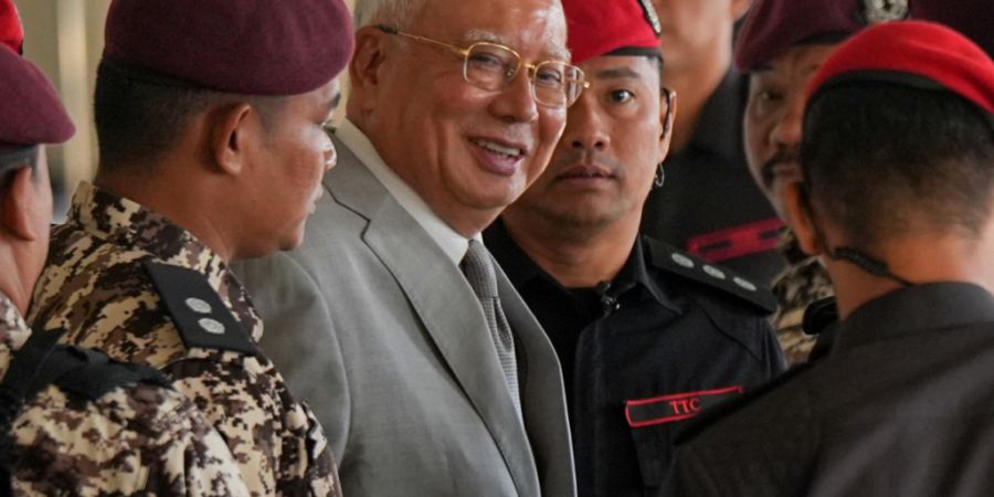 Der ehemalige malaysische Premierminister Najib Razak, Mitte, wird bei seiner Ankunft im Kuala Lumpur High Court Complex von Gefängnisbeamten eskortiert. Foto: Azneal Ishak/AP/dpa
