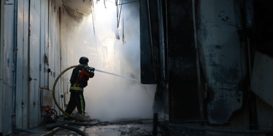 Ein Feuerwehrmann löscht einen Brand im Zentralmarkt von Saporischschja nach einem russischen Angriff. Foto: Kateryna Klochko/AP/dpa