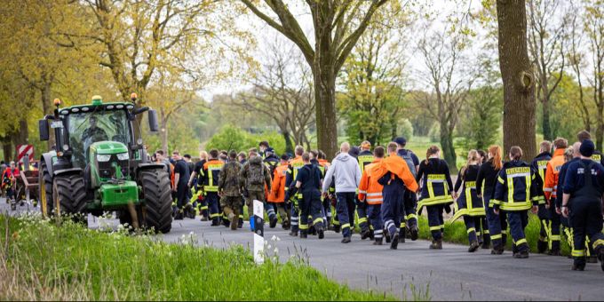 28.04.2024, Niedersachsen, Gräpel: Einsatzkräfte der Feuerwehr gehen eine Strasse im Landkreis Stade entlang. Der sechs Jahre alte Arian aus Elm wird weiter vermisst, die Suche nach ihm geht weiter.