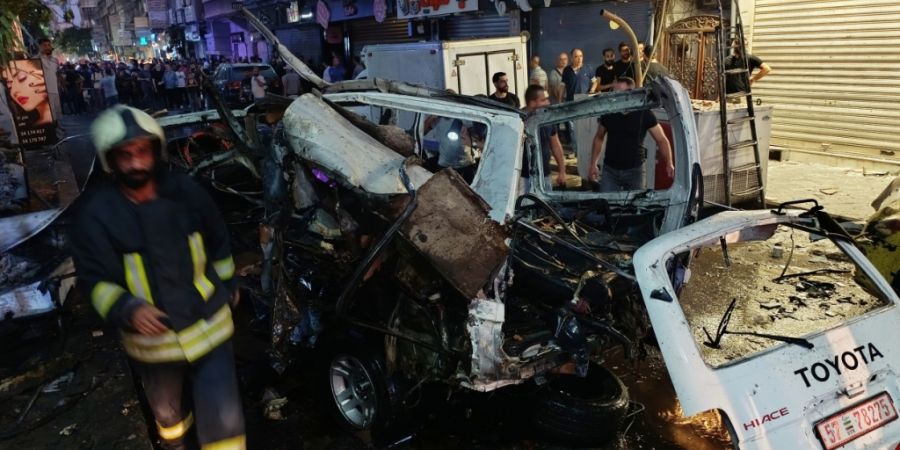 Syrische Feuerwehrleute und Rettungskräfte begutachten am Ort einer Explosion im Vorort Jaramana beschädigte Fahrzeuge. Foto: Abdulrahman Shaheen/AP/dpa