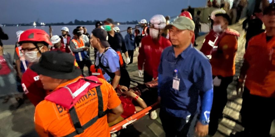 Rettungskräfte tragen in einem Hafen in Banjarmasin einen Überlebenden einer gekenterten Fähre auf einer Trage. Im Inselstaat Indonesien geriet eine Fähre in Seenot. Foto: Iman Satr...