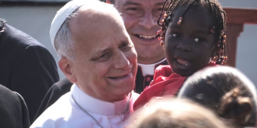 Papst Leo XIV. h‰lt ein kleines M‰dchen im Arm, als er zu einem Treffen mit Migranten im Aufnahmezentrum Las RaÌces in San CristÛbal de La Laguna auf Teneriffa eintrifft. Foto: Ar...