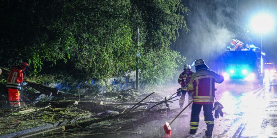 Die Feuerwehr befreit eine Straße von einem umgestürtzten Baum im Ostalbkreis. Foto: Jason Tschepljakow/dpa