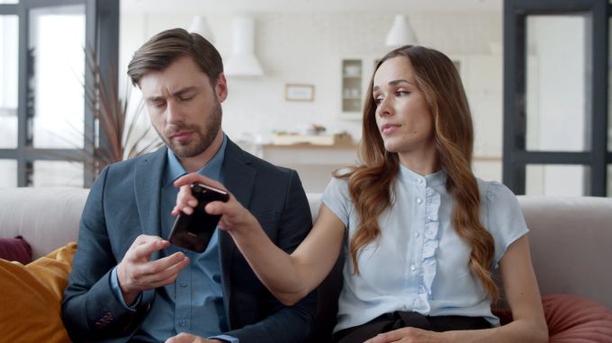 Ist dein Partner in letzter Zeit auffällig viel am Smartphone oder hält Informationen vor dir geheim? Frau mann smarthone skeptisch