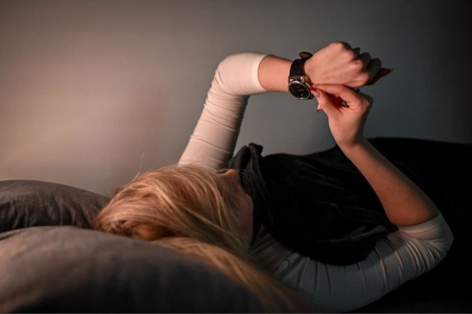 Der Biorhythmus vieler Menschen reagiert empfindlich auf die Zeitumstellung. (Symbolbild) Frau Bett Uhr Zeitumstellung