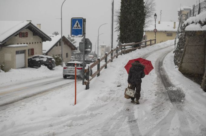 Eine Frau schreitet auf der verschneiten Strasse, am Montag, 23. Dezember 2024 in Ollon, Crans-Montana VS. (Symbolbild) wetterjahr