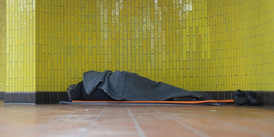 Ein Obdachloser liegt in seinem Schlafsack in einer U-Bahnstation in der Hamburger Innenstadt. 17,7 Millionen Menschen waren 2023 in Deutschland von Armut oder Ausgrenzung bedroht.