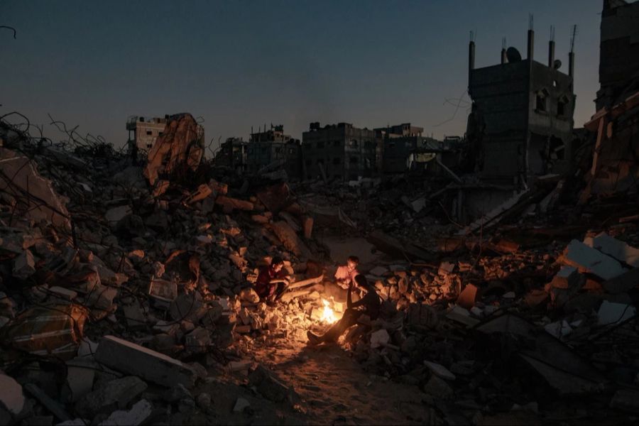 Jugendliche sitzen im Gazastreifen vor einem Feuer. Eine Stromversorgung gibt es hier längst nicht mehr. (Archivbild)