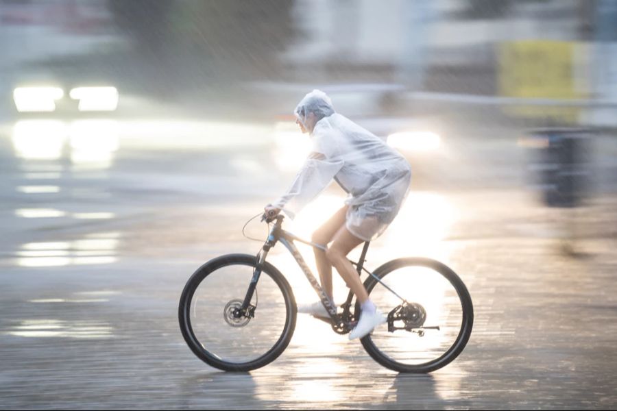 Eine Person fährt mit dem Velo durch den Regen. In der Schweiz dürften die Regenmengen im Rahmen bleiben. (Symbolbild)