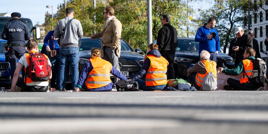 Klimaaktivisten haben sich am Karlsplatz in der Münchner Innenstadt auf die Fahrbahn geklebt und blockieren die Strasse.