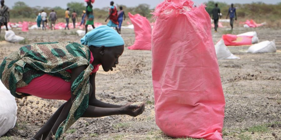 Eine Frau sammelt im südsudanesischen Kandak Hirse vom Boden auf, die in Säcken vom Welternährungsprogramm der Vereinten Nationen über der Stadt abgeworfen wurden.