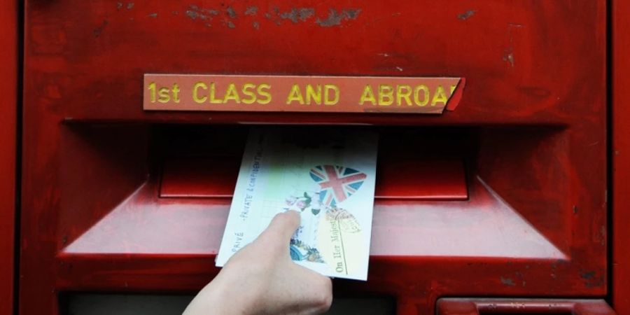 Eine Frau wirft einen Brief in einen Postkasten in London. (Archivbild)