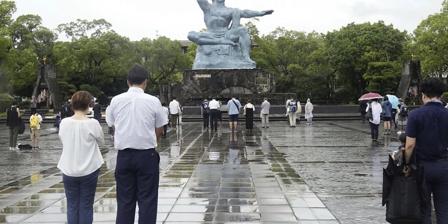 Besucher beten still für die Opfer des US-Atombombenabwurfs vor der Friedensstatue in Nagasaki, Südjapan, zum Zeitpunkt des Bombenabwurfs. Die Zeremonie fand in einem Innenraum statt und wurde wegen des herannahenden Tropensturms Khanun verkleinert. Foto: -/Kyodo News/dpa