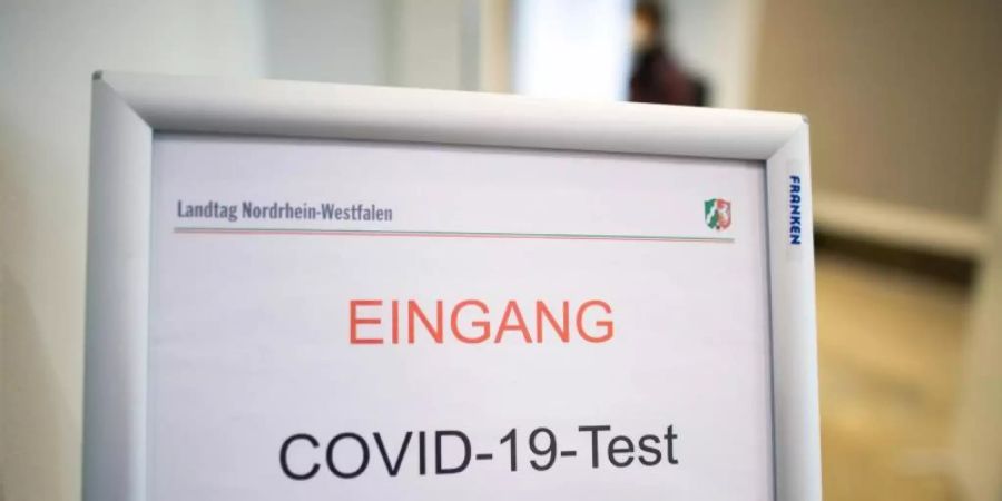 Ein Schild weist auf den Eingang zu einem Covid-19-Testcenter hin. Laut Umfrage lässt dich fast jeder dritte Erwachsene regelmässig testen. Foto: Federico Gambarini/dpa