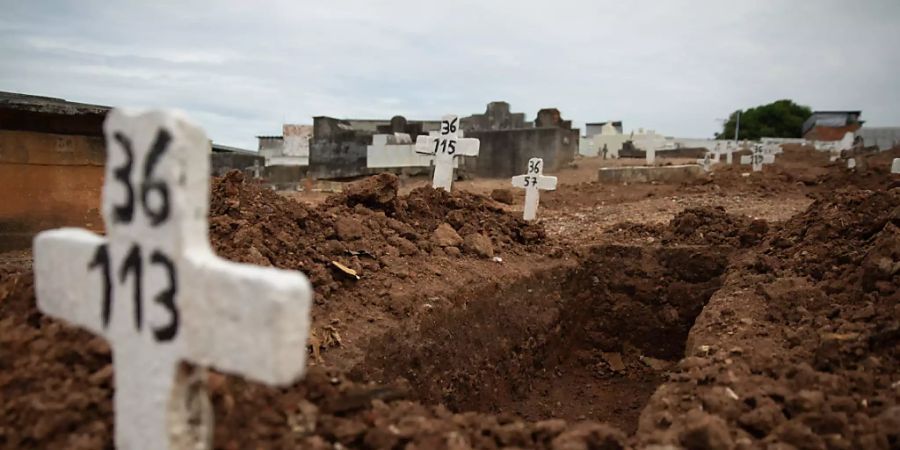 dpatopbilder - Ein einfaches Kreuz ohne Namen und mit einer Nummer steht an einem offenen Grab auf einem Friedhof in Rio de Janeiro. Foto: Fernando Souza/dpa