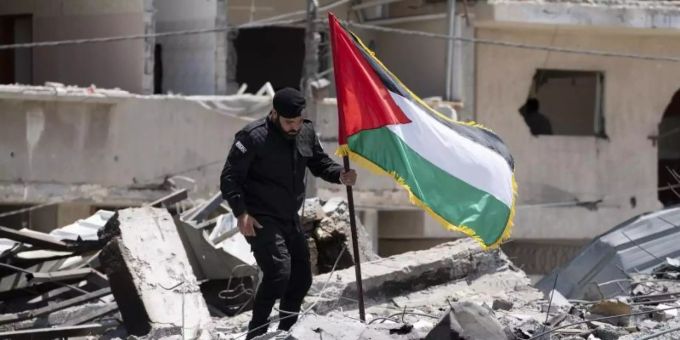 Ein Polizist der Hamas entfernt eine palästinensische Fahne von einem Trümmerhaufen eines Bahnhofsgebäudes, das bei Luftangriffen zerstört worden war. Foto: John Minchillo/AP/dpa Ein Polizist der Hamas entfernt eine palästinensische Fahne von einem Trümmerhaufen eines Bahnhofsgebäudes, das bei Luftangriffen zerstört worden war. Foto: John Minchillo/AP/dpa