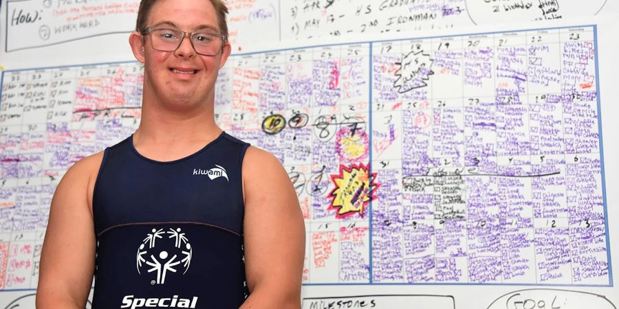 Triathlet Chris Nikic steht in seinem Zimmer vor einer Tafel, auf der er seine Traingseinheiten notiert hat.