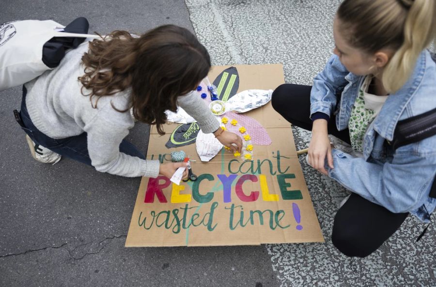 Zwei Frauen basteln ein Plakat, das am Klimastreik hochgehalten wird.