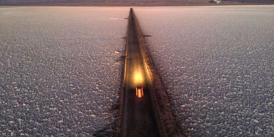 Ein Auto fährt auf einer Strasse durch den Salar de Atacama in der Nähe der Lithiummine Albemarle in Chile.