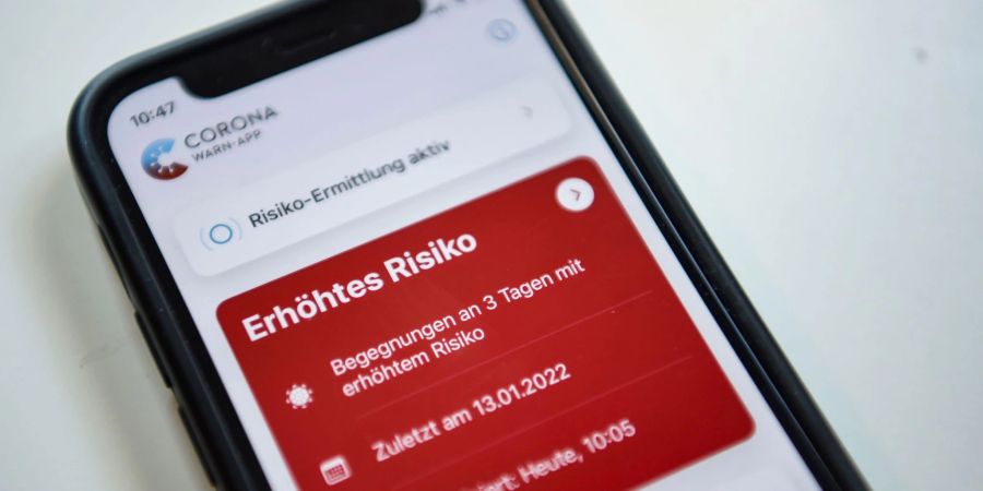 Auf einem Smartphone zeigt die geöffnete Corona-App ein erhöhtes Risiko an.