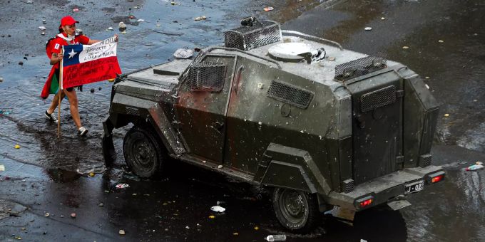 Eine Demonstrantin hält während eines Protests eine chilenische Flagge und steht vor einem gepanzerten Polizeifahrzeug. Die Zahl der Todesopfer bei den schweren Unruhen in Chile ist nach offiziellen Angaben auf 15 gestiegen. Proteste in Chile