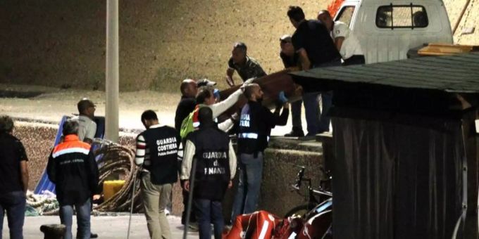Mitarbeiter der italienischen Küstenwache bringen im Hafen von Lampedusa einen Sarg von Bord. Lampedusa