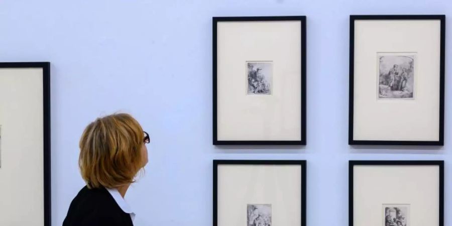 Eine Museumsmitarbeiterin geht durch die Sonderausstellung mit ausgewählten Meistergrafiken von Rembrandt. Foto: Jens Büttner/zb/dpa