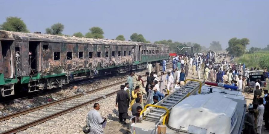 Ein Rettungswagen steht neben dem ausgebrannten Personenzug. Foto: Siddique Baluch/AP/dpa