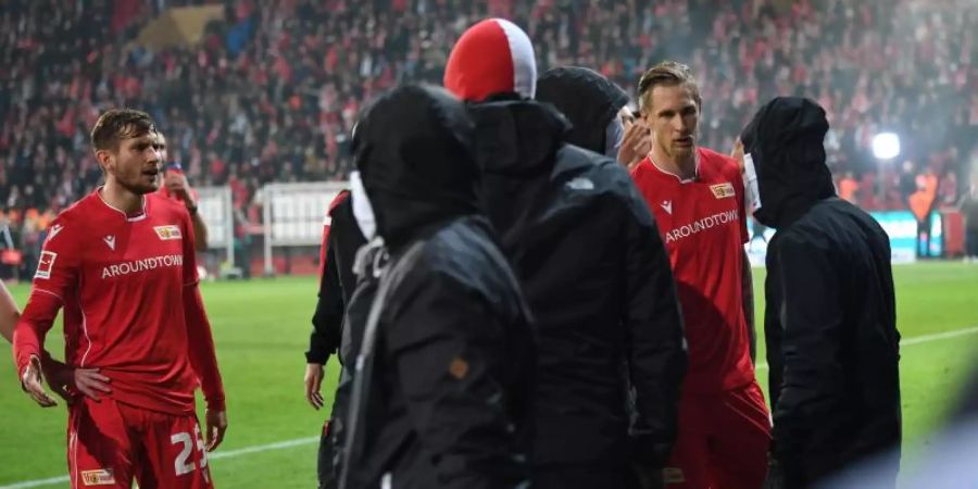 Union-Spieler versuchen nach dem Abpfiff vermummte Fans zu beschwichtigen. Foto: Britta Pedersen/dpa