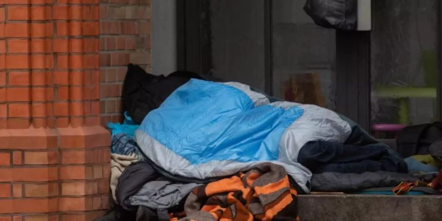 Ein Obdachloser liegt in einem Eingang einer Kirche in Berlin. Obdachlos sind den Zahlen der Wohungslosenhilfe zufolge etwa 41.000 Menschen in Deutschland. Foto: Paul Zinken/dpa